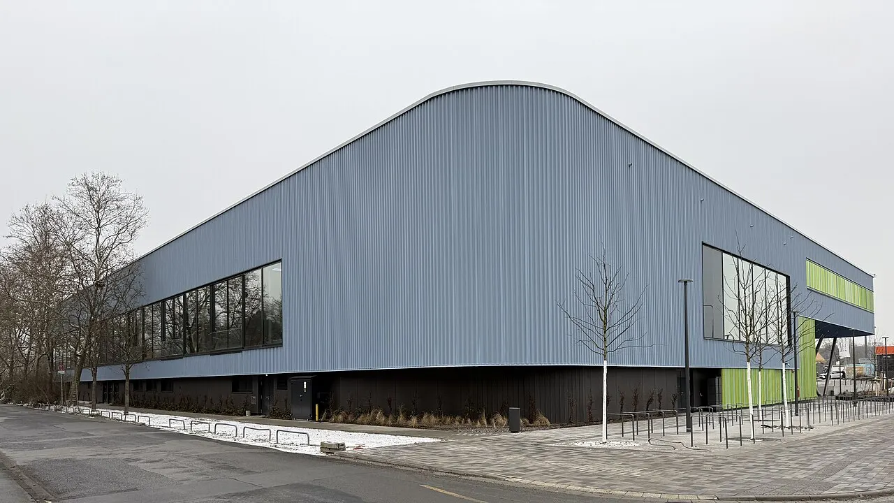 Graublau verkleideter Neubau des Main Bad Bornheim in Frankfurt mit großen Fensterflächen und grüner Fassade am Eingang