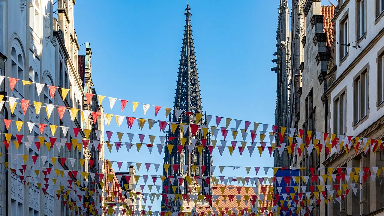 Wimpelketten in Rot, Gelb und Weiß über dem Prinzipalmarkt in Münster, dahinter der Turm der Lambertikirche
